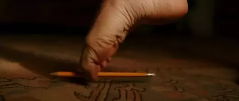 Charlize Theron picks up a pencil in “The Last Face”